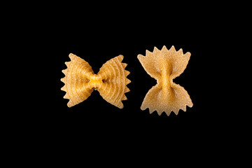 pasta from durum wheat Farfalle, bows, unprepared, raw pasta handmade on black background isolated