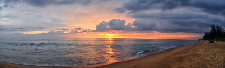 Phuket beach sunset, colorful cloudy twilight sky reflecting on the sand gazing at the Indian Ocean, Thailand, Asia.