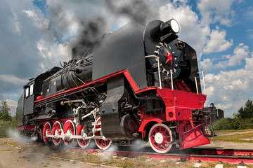 Fototapeta na wymiar vintage steam train hurtling at speed along the rails close-up, retro vehicle, steam engine