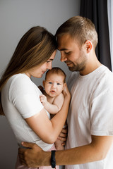 Fototapeta premium Parents holding their cute little baby and looking at her