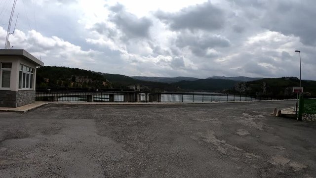 4k POV of a coming at Tablilla's reservoir and driving on it in Nerpio, Murcia, Spain. Driving crossing a dam on a cloudy day in a south Europe region, mediterranean geography.