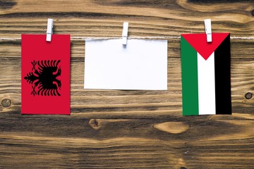 Hanging flags of Albania and Palestine attached to rope with clothes pins with copy space on white...