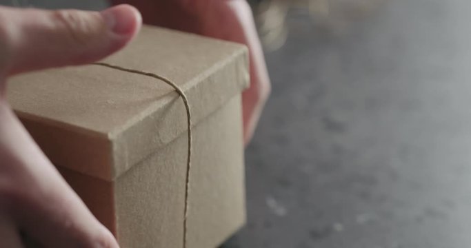 Slow motion man hand ties bow on brown paper box