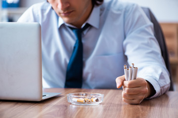 Male employee smoking cigarettes at workplace