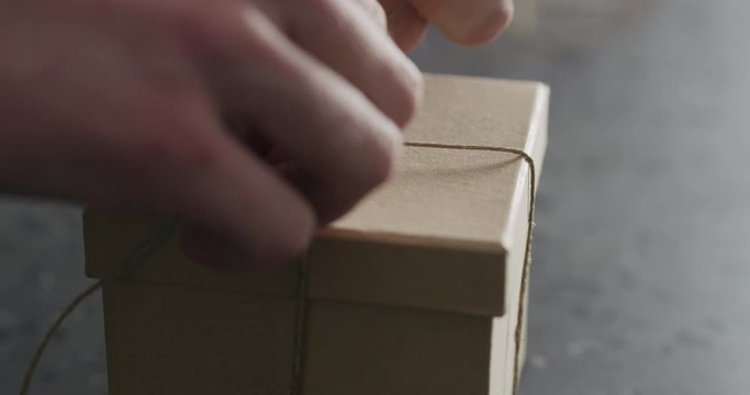 Slow motion man hand ties bow on brown paper box