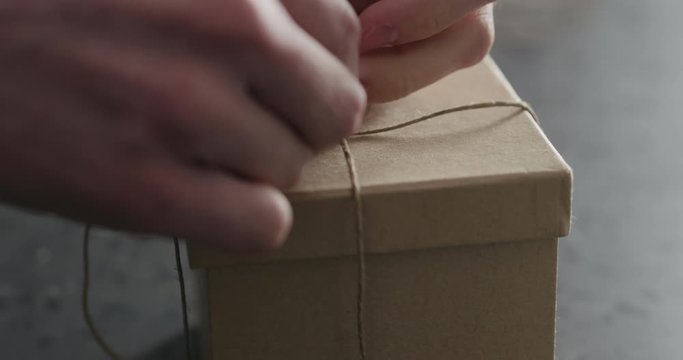 Slow motion man hand ties bow on brown paper box