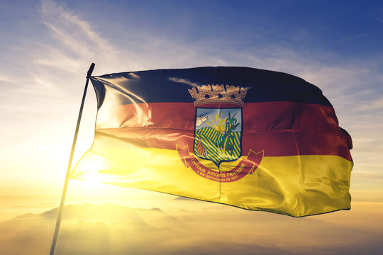 Teofilo Otoni of Brazil flag waving on the top sunrise mist fog