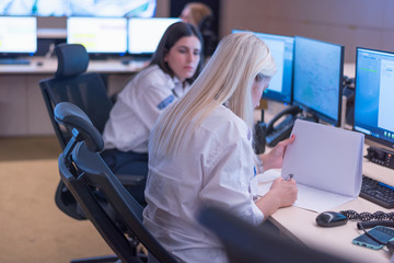 Security guard monitoring modern CCTV cameras in surveillance room. Two Female security guards in surveillance room.