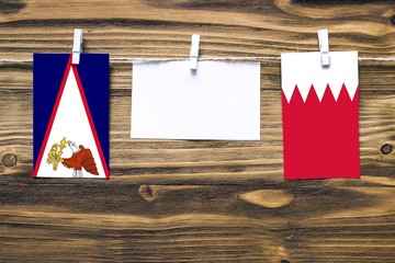 Hanging flags of American Samoa and Bahrain attached to rope with clothes pins with copy space on...