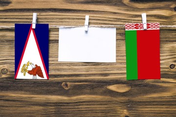 Hanging flags of American Samoa and Belarus attached to rope with clothes pins with copy space on...