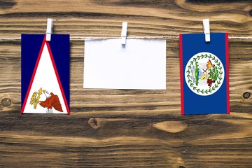 Hanging flags of American Samoa and Belize attached to rope with clothes pins with copy space on...