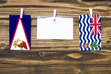 Hanging flags of American Samoa and British Indian Ocean Territory attached to rope with clothes...