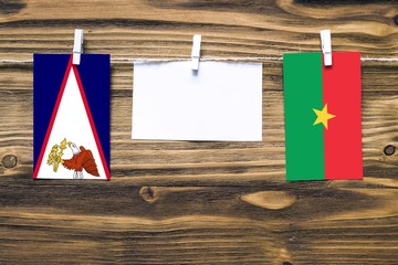 Hanging flags of American Samoa and Burkina Faso attached to rope with clothes pins with copy space...