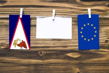 Hanging flags of American Samoa and European Union attached to rope with clothes pins with copy...