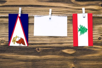 Hanging flags of American Samoa and Lebanon attached to rope with clothes pins with copy space on...