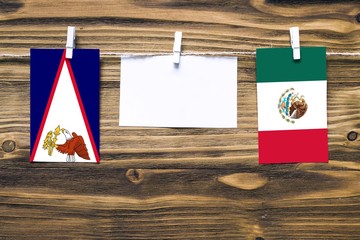 Hanging flags of American Samoa and Mexico attached to rope with clothes pins with copy space on...