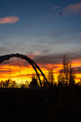 Fototapeta na wymiar Sunset in a Mediterranean city with the silhouette of the metal structure of a suspended bridge.