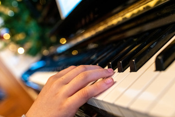 Child playing a song at the piano, closeup of his hands.