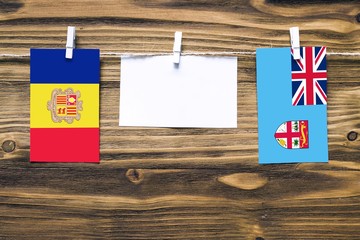 Hanging flags of Andorra and Fiji attached to rope with clothes pins with copy space on white note...
