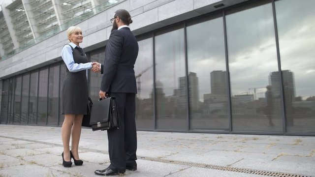 Man and woman shaking hands and smiling, business partners getting acquainted