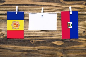Hanging flags of Andorra and Haiti attached to rope with clothes pins with copy space on white note...