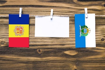 Hanging flags of Andorra and San Marino attached to rope with clothes pins with copy space on white...