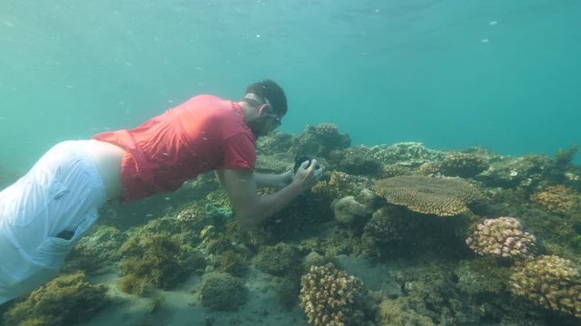 A tourist making photos and videos underwater using a digital camera. Strange