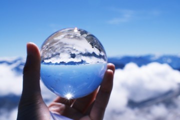 Hand holding crystal ball showing  Reflection of landscape from Zugspitze. 