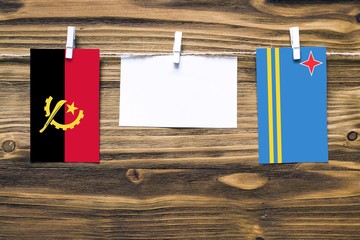 Hanging flags of Angola and Aruba attached to rope with clothes pins with copy space on white note...