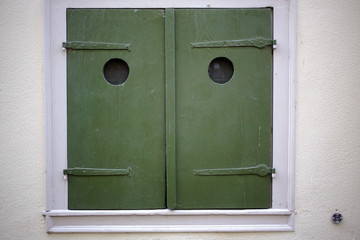 Close-up of green closed window shutters on white wall