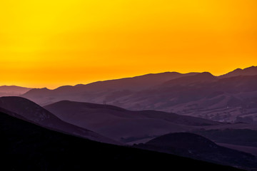 Yellow Sunrise over Silhouetted Mountains