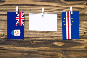 Hanging flags of Anguilla and Cape Verde attached to rope with clothes pins with copy space on white note paper on wooden background.Diplomatic relations between countries.