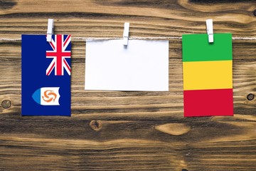 Hanging flags of Anguilla and Mali attached to rope with clothes pins with copy space on white note paper on wooden background.Diplomatic relations between countries.