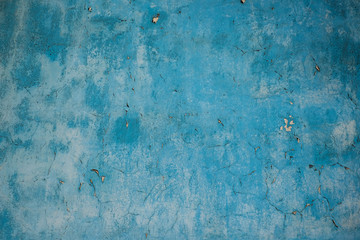 Abstract blue grungy wall with various shades of blue, light and dark patches and some flaking paint, empty background or backdrop graphic material.