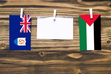 Hanging flags of Anguilla and Palestine attached to rope with clothes pins with copy space on white...