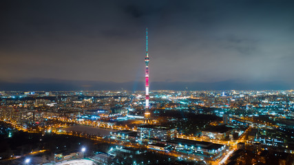 Obraz premium Motion of Ostankino tower on the night, view from above. Picturesque aerial panorama of Moscow center with bright glittering buildings, streets and traffic.