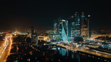 Obraz na płótnie Canvas Picturesque aerial panorama of Moscow City Business Center on the night with bright glittering lights of buildings, streets and traffic. Camera slowly moves away showing amazing cityscape.