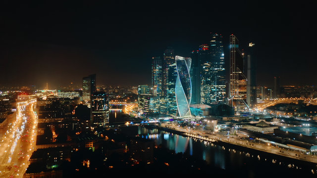Beautiful view from above to Moscow City Center on the night with bright glittering lights of buildings, streets and traffic. Camera slowly moves towards skyscrapers showing amazing cityscape.