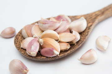 Garlic cloves on a wooden ladle  on white background