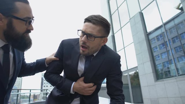 Man feeling pain in chest and labored breathing walking with boss, heart attack