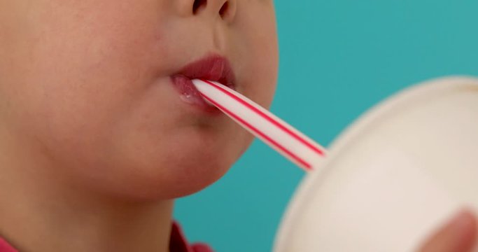 Cute little baby drinking milkshake blue background