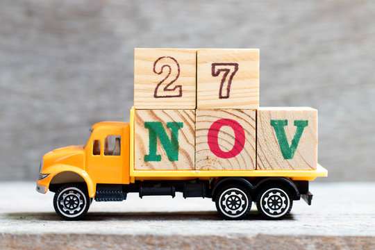 Truck hold letter block in word 27nov on wood background (Concept for date 27 month November)