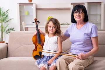 Old lady teaching little girl to play violin