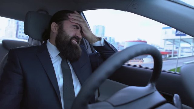 Man in suit suffering acute migraine sitting in car, hard day, health problems
