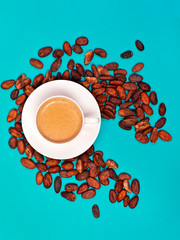 Cup of cacao drink with cocoa beans on azure background. Top view.