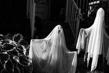 Halloween decoration at the front yard doors.creepy ghosts on the dark stairs background.Scary decoration style on the street neighbourhood.