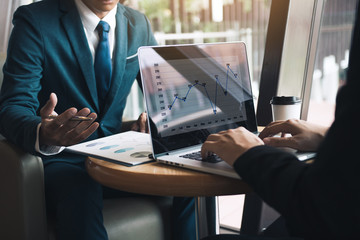 Two businessmen are talking about the results of operations in the company financial statements on the computer screen.