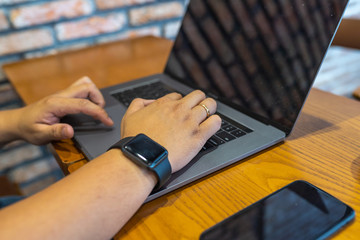 Human hand typing laptop keyboard on wooden table
