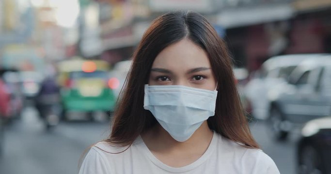 Woman wearing mask and looking to camera at city. Health care and medical concept.