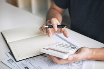 Man use calculators and documents that calculate expenses in the home office.